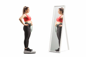 Young female in sportswear weighing on a medical scale